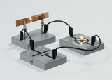 The picture shows an experiment kit with two grey platforms containing electrical contacts and a light bulb. A metal plate is connected to terminals to conduct electricity and demonstrate physics principles.