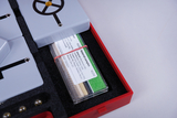 The picture shows an experiment box with various material samples and technical components that are used to carry out experiments in the educational field. The samples include materials such as aluminum, glass and wood that can be used for analysis.