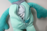 The picture shows a teal-colored stuffed animal with a zipper along the side. The zipper is open and a label is visible inside that contains information about the manufacturing process.