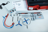 The picture shows a wind energy experiment kit that includes various components such as motors, cables and propellers. It also includes instructions and a red storage box to organize the materials.