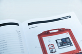 The picture shows a page from a catalog for experimental materials, which shows a layout plan for a wind energy set. The picture shows a red suitcase filled with various experimental materials.