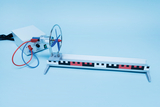 The picture shows an experimental device that includes a motor with a propeller and a guide rail. It is used to carry out experiments in the field of physics, in particular to illustrate forces and movements.