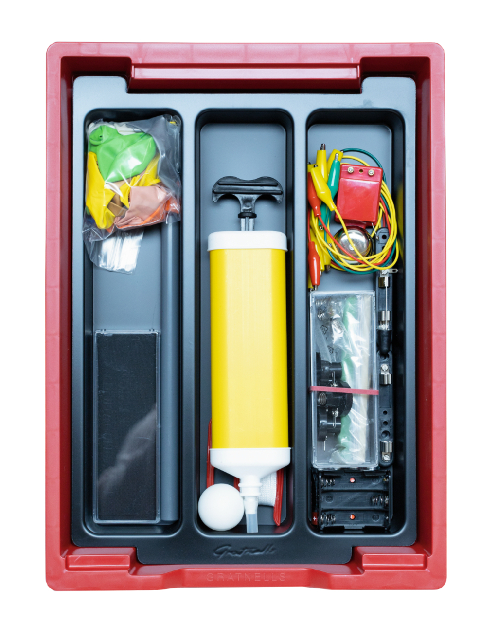 The picture shows an experiment kit arranged in a red container. It contains, among other things, balloons, an air pump, various wires and an electrical toy, ideal for school projects in science classes.