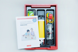 The picture shows an experiment kit for children that contains materials for conducting experiments with electricity. Next to the contents is a booklet that provides instructions for the experiments and is aimed at kindergarten children.