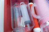 The picture shows a transparent box with various experimental equipment, including glass flasks, syringes and measuring containers. Everything is neatly arranged and ready for use in education.