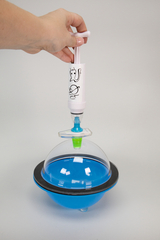 The image shows a hand holding a pump over a clear blue container. The container has a glass dome sitting on a black rim and contains a liquid that has potential use for experiments in education.