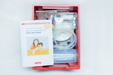The picture shows a red box with experimental materials for children, including pipettes, glasses and an accompanying book. The book is about experiments with light and sound and is aimed at kindergartens.