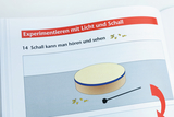 The picture shows an illustration from a textbook about experiments with light and sound. It deals with the perception of sound and shows a picture of an instrument and some musical note symbols.