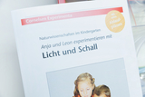 The picture shows a book about scientific experiments in kindergarten, in which children work with light and sound. It contains instructions and flow charts for carrying out the experiments.