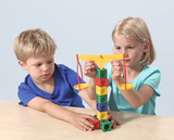 In the picture, a boy and a girl are experimenting with a colorful seesaw. They use different colored blocks to test balance and learn how weight and balance work.