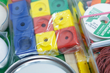 The picture shows a variety of experimental materials, including colorful cubes and rolls, housed in a transparent packaging. The set is complemented by various round objects and rubber bands, suitable for hands-on learning activities.