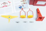 The picture shows experimental materials, including a yellow device with a magnet, two brackets and several pieces of metal. In the background, a manual is visible that contains instructions for experiments with levers, pulleys and magnets.