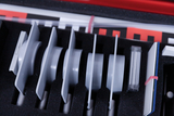 The picture shows the inside of a case with various experimental materials for educational purposes. You can see several round and rectangular components arranged in precisely fitting foam compartments.
