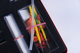 The picture shows a collection of experimental materials organized in a case with foam inserts. In addition to transparent tubes and colorful balloons, various accessories such as small caps and rods are also included.