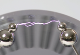 The image shows two metallic balls connected by an electric spark. This spark illustrates a physics experiment commonly used in school education to illustrate concepts of electricity and current.