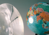 The image shows a see-through lens on the left and a colorful globe on the right. These objects are probably in the context of experiments or teaching materials used in education.