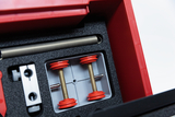 The image shows a red experiment kit organized in a foam interior. It contains various components, including metal rods and red wheels, that can be used for educational science experiments.