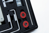 The picture shows a set of experimental materials consisting of various components such as red magnets and metallic rods, all neatly arranged in a black foam insert. This accessory is intended for educational purposes in Germany.