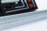 The picture shows an aluminum ruler with precise measuring scales, some of which are in sharp focus. In the background is a case with other experimental accessories, which is ideal for educational purposes.