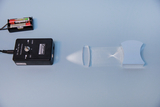The picture shows an experimental device with a laser and a lens that creates a pattern of light rays. Next to the device are two batteries that are used to supply energy.