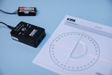 The picture shows an experimental device with a control box and a laser beam that is projected onto a measuring sheet with a semicircle and scales. Next to the box there is a battery compartment to power the device.