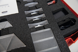The picture shows a set of optical experiment materials arranged in a padded case. The items included include various prisms and a measuring device, which can be used for teaching purposes in the natural sciences.