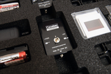 The picture shows an experimental device with a switch for a laser and an LED, which is stored in a padded box. Next to the device, batteries and other materials for experiments in the educational field are visible.