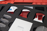 The picture shows a set of optical experiment materials arranged in a protective foam section of a red box. It contains several reflective and transparent lenses and a dimension sheet to support experiments in the educational field.