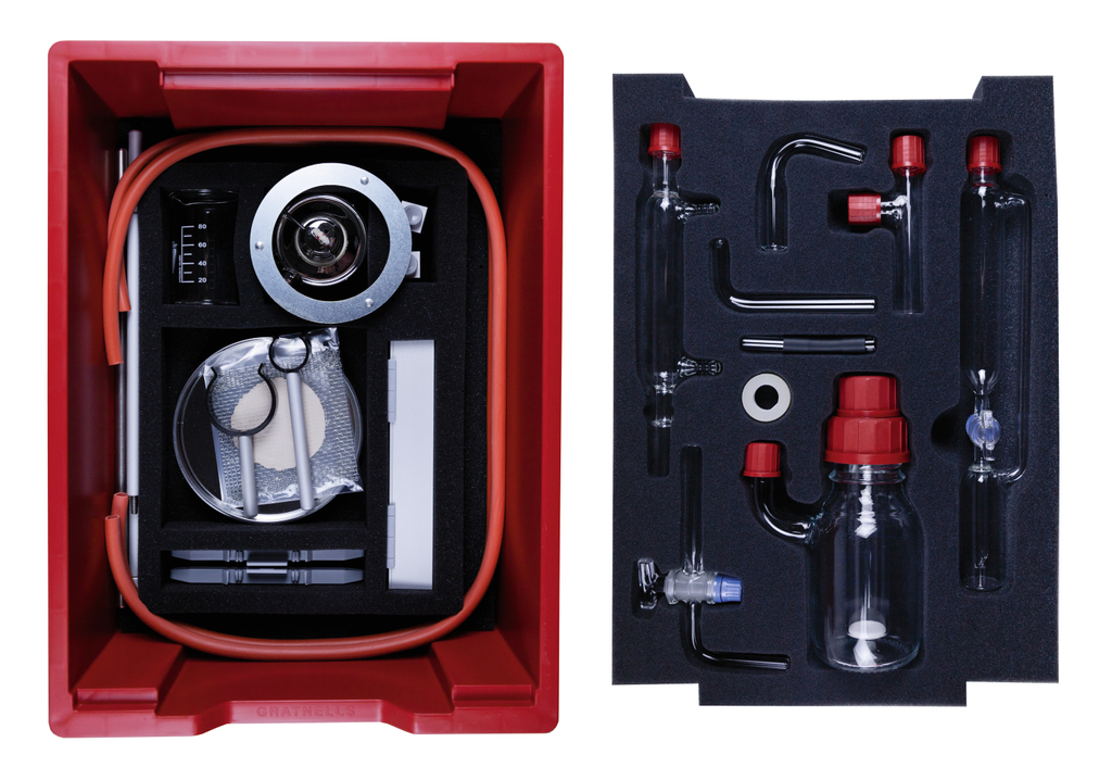 The picture shows a red experiment box containing various laboratory equipment and supplies, including glass tubes, measuring beakers, and a siphon pump. All parts are securely fitted in foam to ensure neat storage.