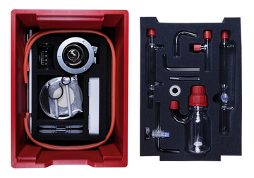 The picture shows a red experiment box containing various laboratory equipment and supplies, including glass tubes, measuring beakers, and a siphon pump. All parts are securely fitted in foam to ensure neat storage.