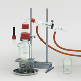 The picture shows a chemical apparatus consisting of a glass container, tubing and a heater, which is used for experiments in education. The apparatus is probably used for distillation or similar experiments in chemistry.