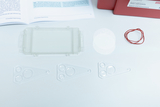 The picture shows various experimental materials, including a transparent box, several microlenses, two white sheets of foil and a rubber band. These items could be used for educational science experiments.