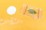 The picture shows various experimental devices on a yellow background, including a container with a green leaf and two magnified lenses. There are also two transparent pieces of furniture and a white round card next to it.
