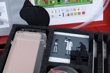 The picture shows an experiment box with various scientific utensils, including a transparent container and an illustration card. The card shows pictures of figures in different situations and an overview of the materials included.