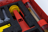 The image shows a collection of experimental tools organized on foam inserts in a red case. Among other things, you can see transparent syringes, a yellow wheel and a red measuring device that can be used for various scientific experiments.