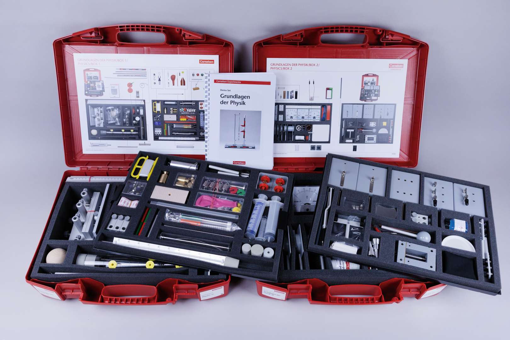 The picture shows two red suitcases filled with experimental materials and equipment for conducting physics experiments, as well as an accompanying book with instructions. All materials are carefully arranged in foam inserts to ensure easy handling.