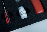 The picture shows a compact storage box with various experimental materials. The focus is on a glass container with citric acid, labeled with information about its suitability for consumption, and a screwdriver made of red plastic.