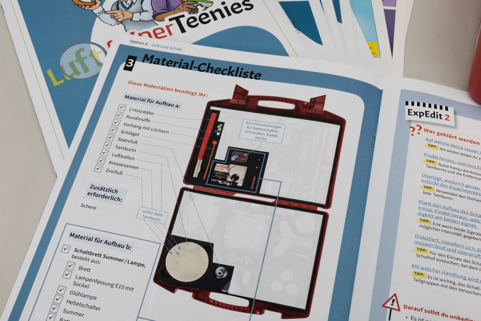 The picture shows a material checklist for an experimental project in the educational sector. In a red case, various materials are listed that are needed for the construction, including wooden sticks, a tambourine and other components.