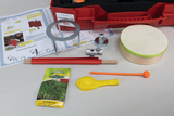 The picture shows an experiment kit with various materials such as a drum, a packet of cress seeds, several tubes, a balloon and instructions for conducting experiments with air. Everything is arranged in a red case designed for educational purposes.