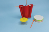 The picture shows various experimental materials, including a red curtain, a yellow table with something on it, and a large drum with an orange baton. These items could be used for various educational or experimental activities in the classroom.