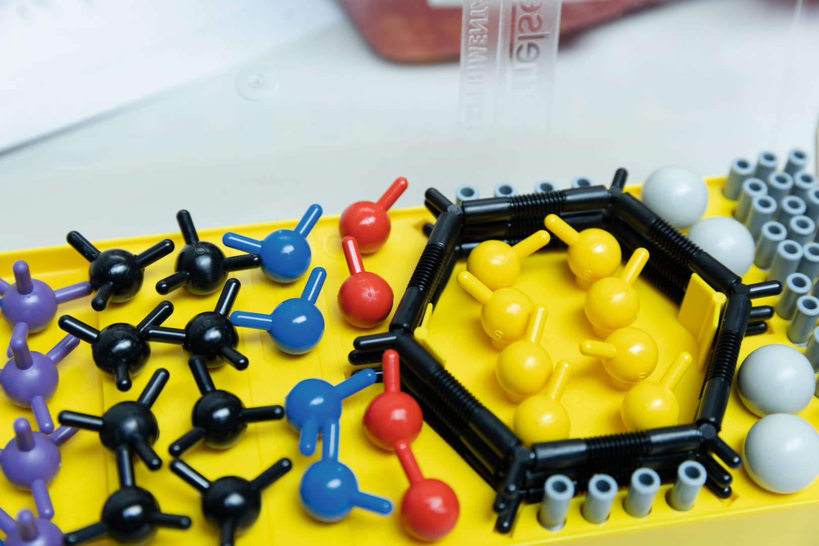 The image shows a colorful model kit arrangement of molecules and atoms on a yellow base. Different colors represent different chemical elements, which is suitable for educational experiment needs.