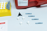 The picture shows a molecular construction kit with various colorful components for creating models. Visible are a yellow base with white and gray balls and instructions in the form of a sheet.