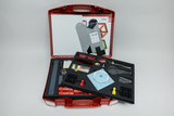 The picture shows a red suitcase filled with various experimental materials for the classroom. It contains tools, holders, colored objects and instructions that can be used for practical experiments.