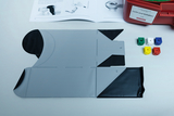 The image shows an experiential learning resource consisting of a flexible two-tone mat and colorful cubes to support experiences with light and shadow. Above this is an illustrated manual containing instructions for use.