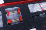 The picture shows a section of an experiment box arranged on a black, foam-filled interior. You can see two red weights with gold rods, which are probably used for physics experiments.