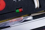 The picture shows equipment for experiments packed in a padded container. Visible components include a special syringe, colored chips and a spring mechanism used for educational purposes.