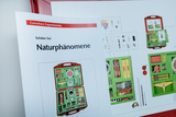 The picture shows a brochure for a student set called &quot;Natural Phenomena&quot; from the online shop for experimental supplies. Next to the brochure you can see an overview of the experimental kit, which contains various materials and tools.