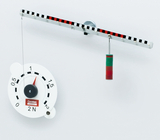 The picture shows an experimental setup for demonstrating forces. A spring balance is suspended from a horizontal bar and connected to colored weights to measure tensile force.
