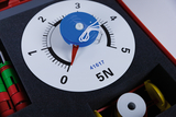 The picture shows an experimental device with a scale from 0 to 5 Newtons, which is used to measure forces. The blue knob is connected to a string, which is probably used for experiments.