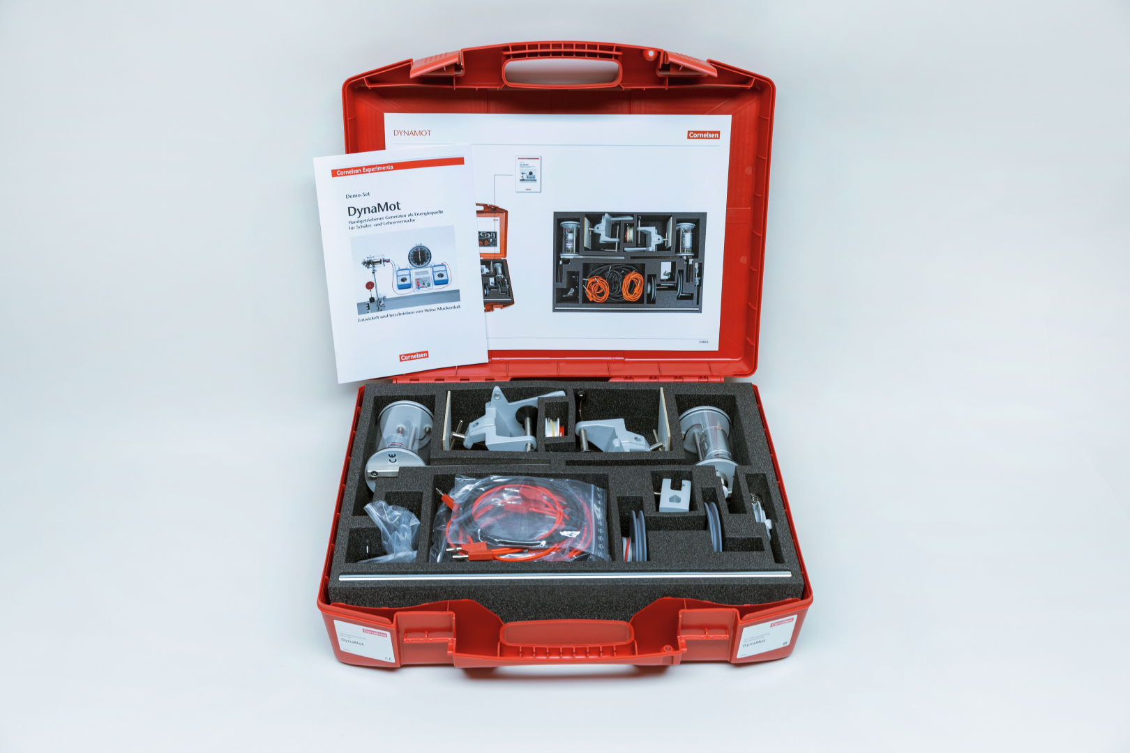 The picture shows an experimental kit called &quot;DynaMot&quot; housed in a red case. The case contains various components and a manual for conducting experiments on generating voltage and power.